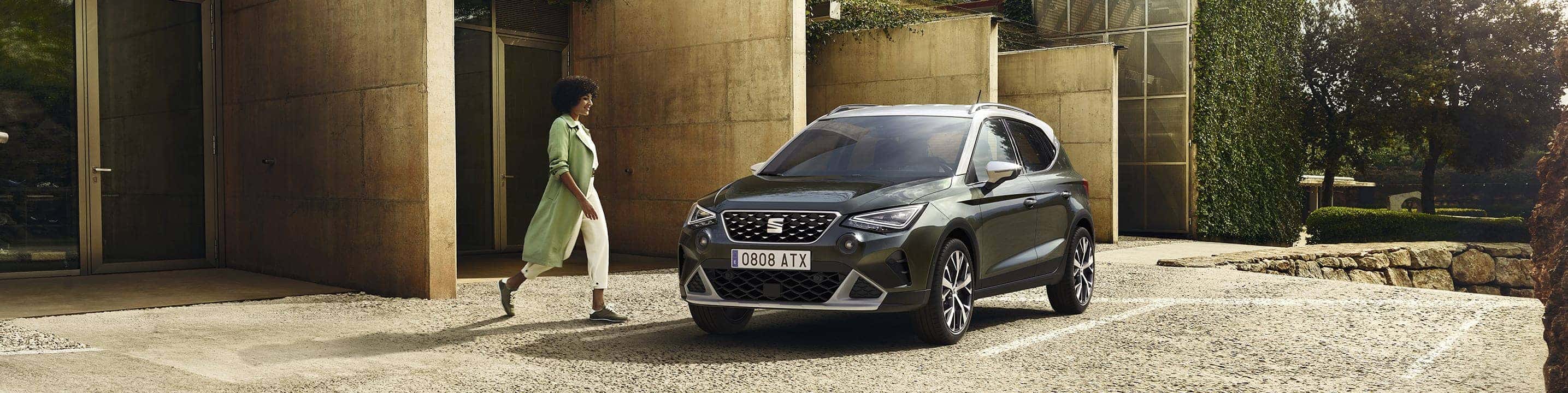 Woman walking to SEAT Arona dark camouflage colour