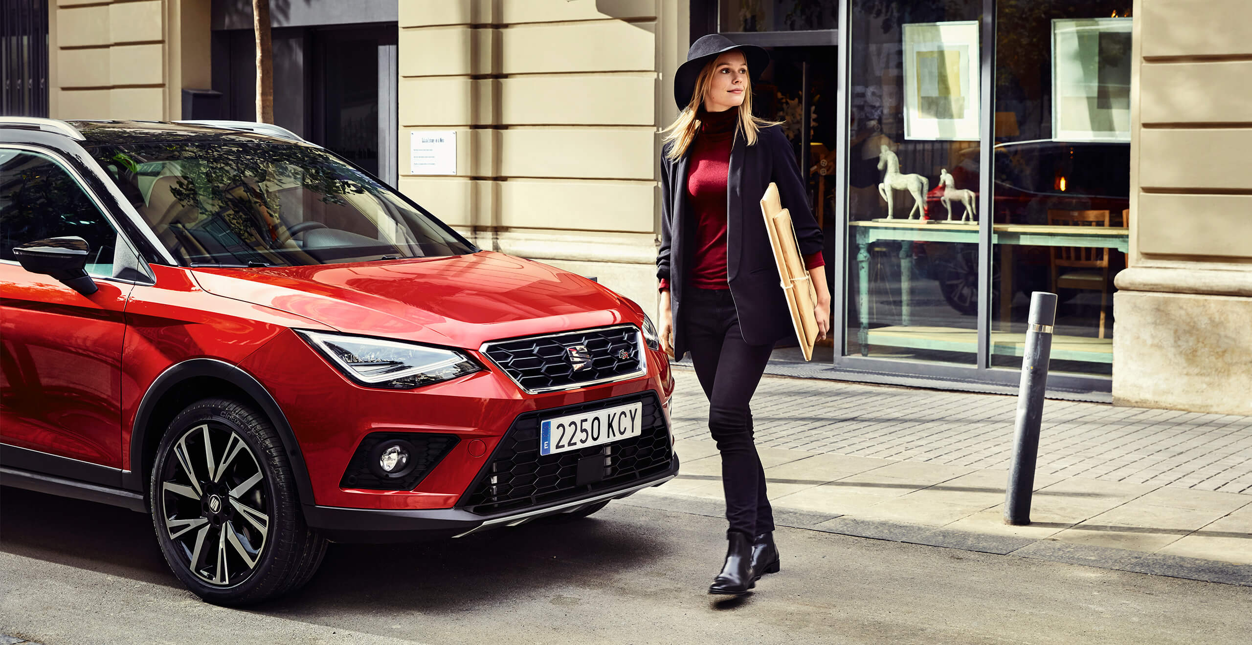 SEATi uute autode teenused ja hooldus – naine kõnnib SEAT Arona crossover SUV ees