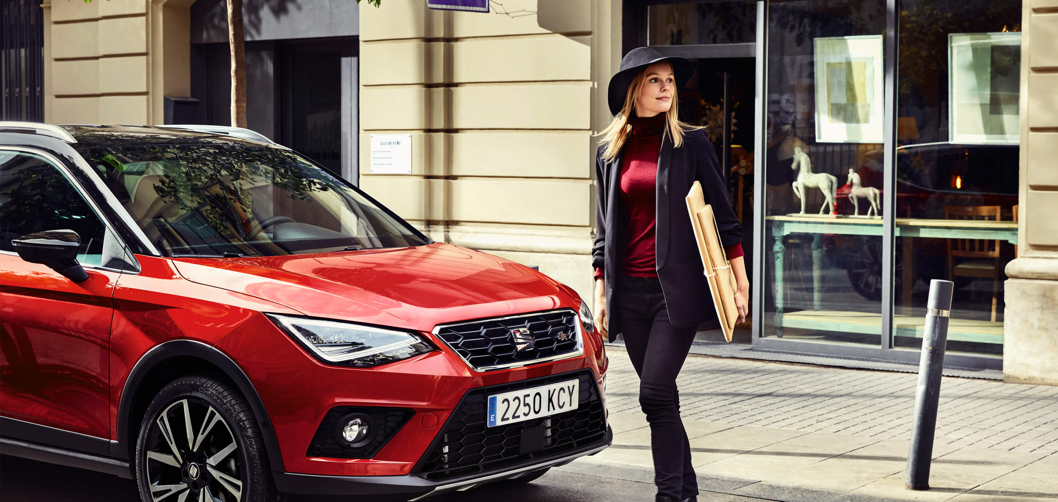 SEATi uue auto teenindus, tehnoülevaatuse eelne kontroll – naine jalutab punase SEAT Arona linnamaasturi ees. SUV
