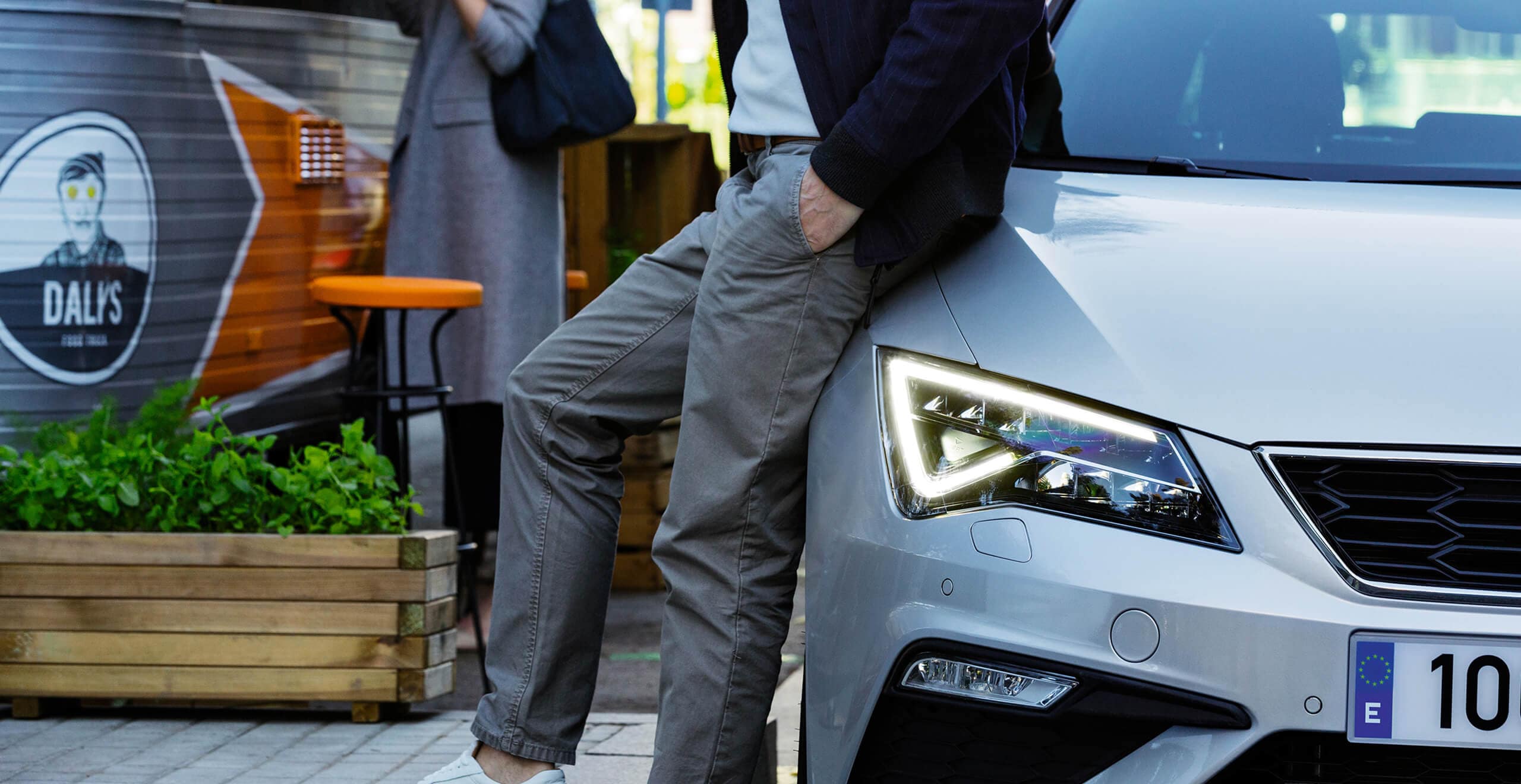 SEAT Service and Maintenance – suited man leaning on the hood of a SEAT hatchback car