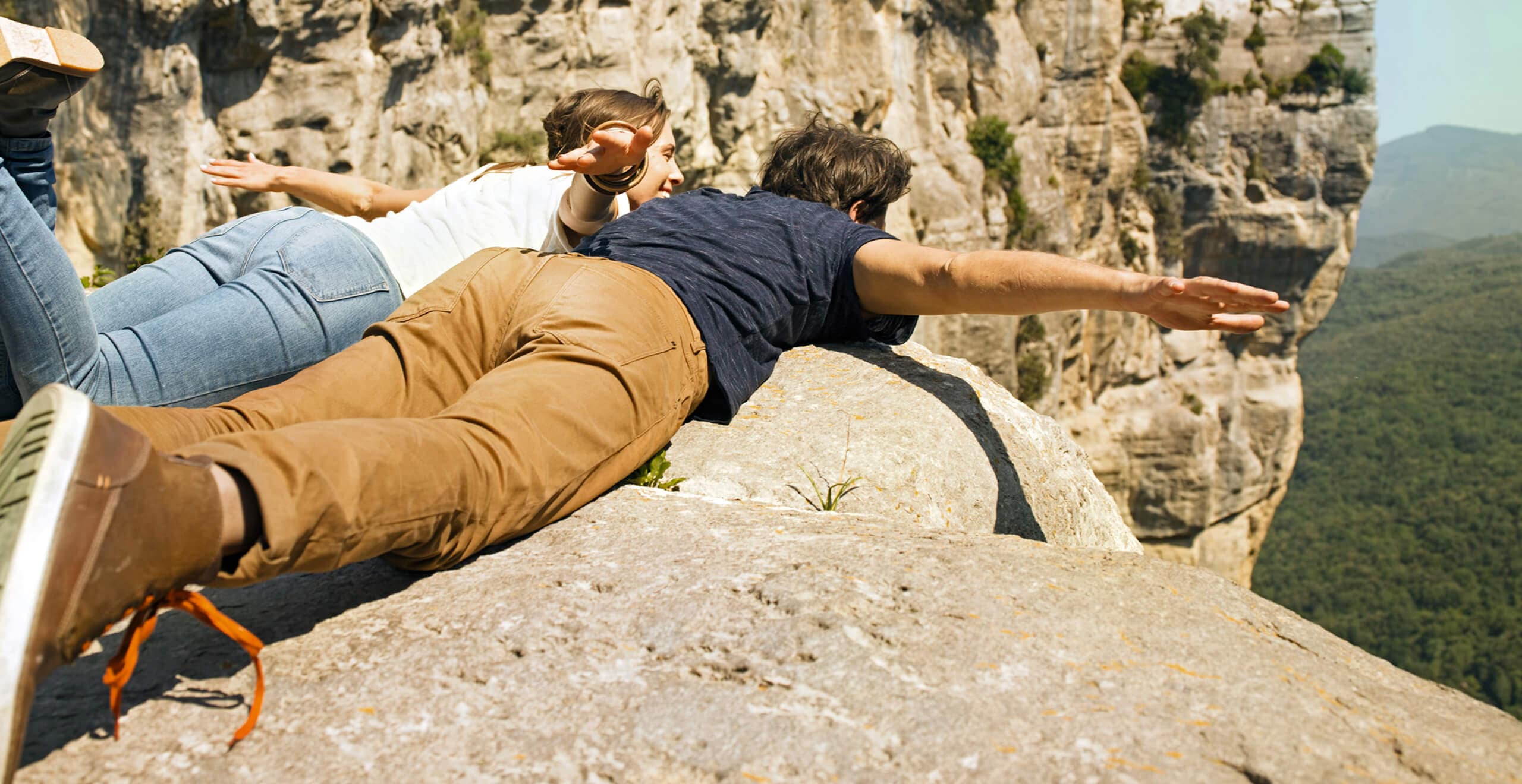 SEAT new car services and maintenance – Two people overlooking the cliff drop laying down on mountain tops