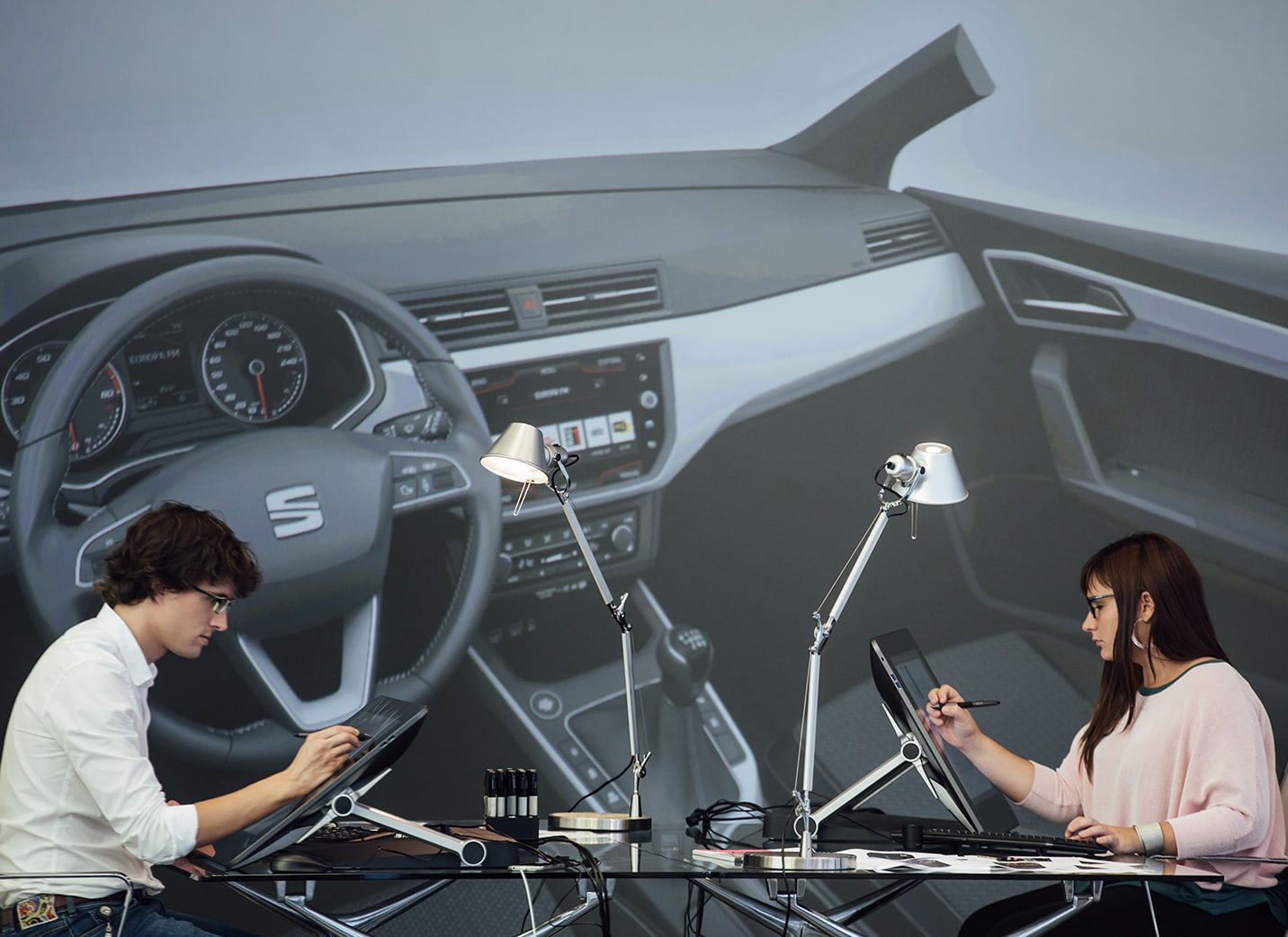 Kaks uue auto disainerit joonistamas spetsiaalsele ekraanile, taustaks foto vaatega auto siseruumile – SEAT tööandjana
